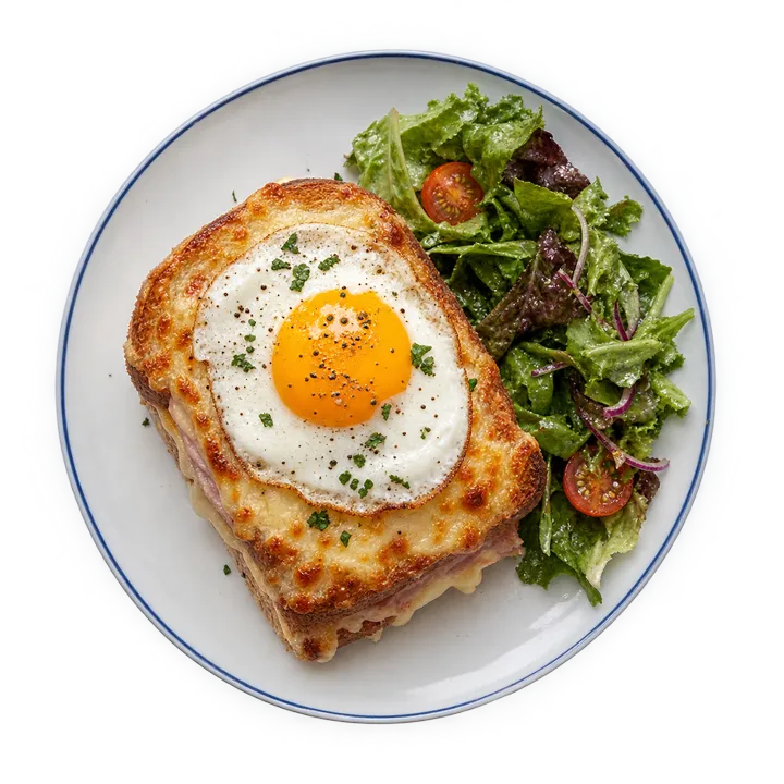 Un croque-madame avec un œuf au plat et une petite salade