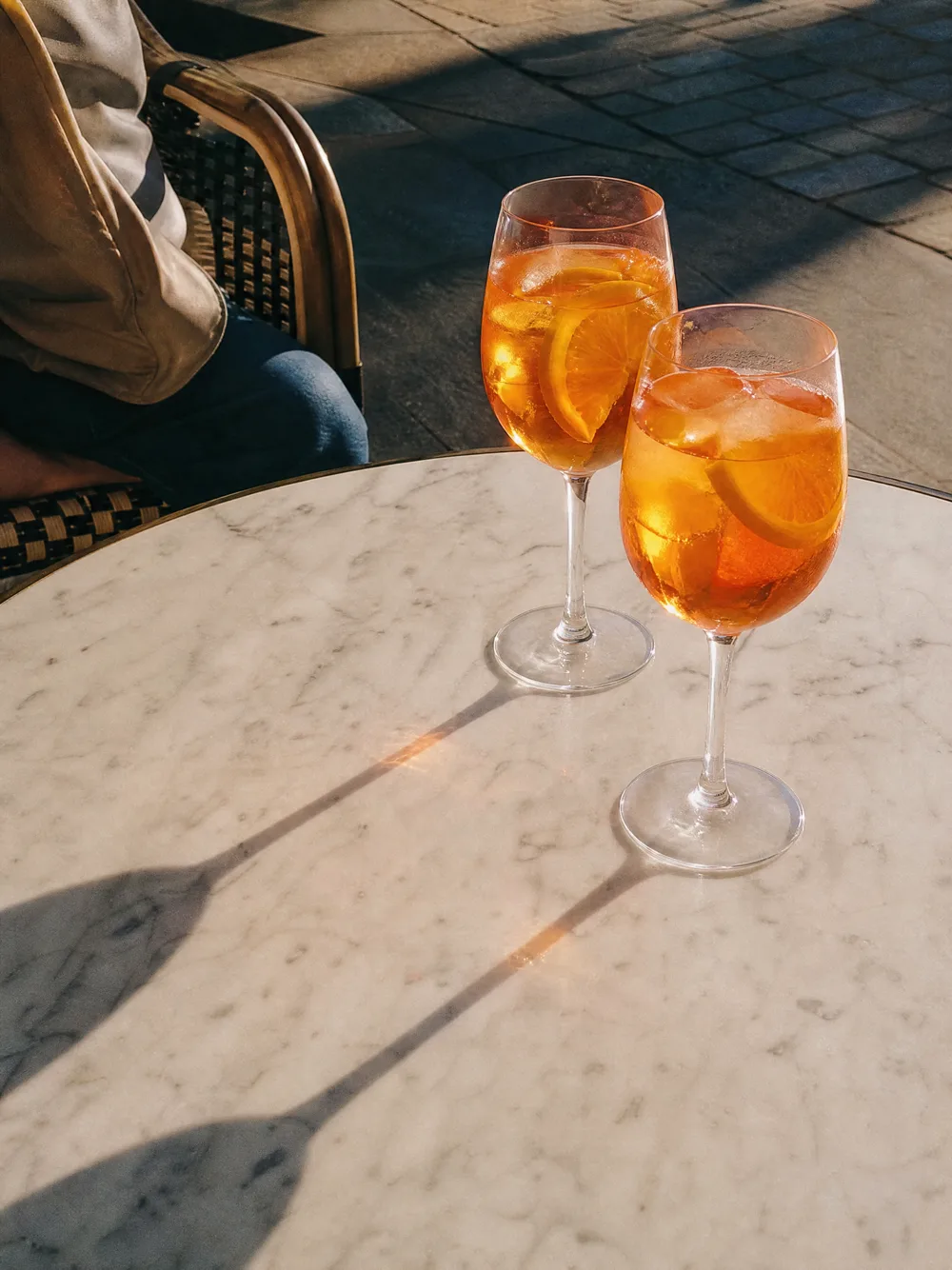 Deux spritz sur une table de marbre au soleil du soir