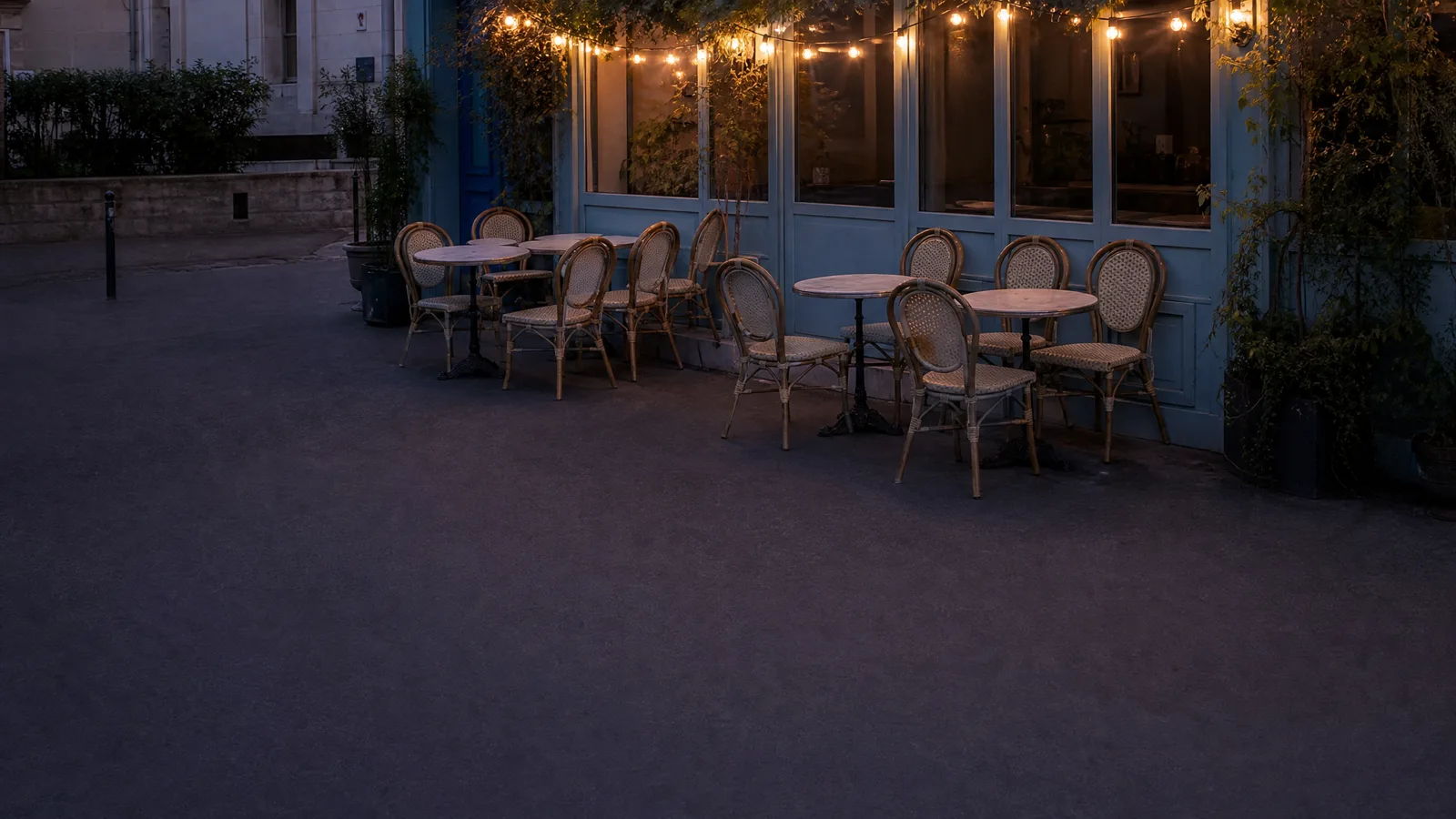 La terrasse à la tombée du jour, une guirlande d'ampoules allumée au-dessus des tables